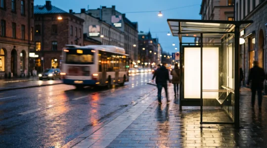 Vue large d'un abribus publicitaire intégré dans une rue urbaine animée au crépuscule